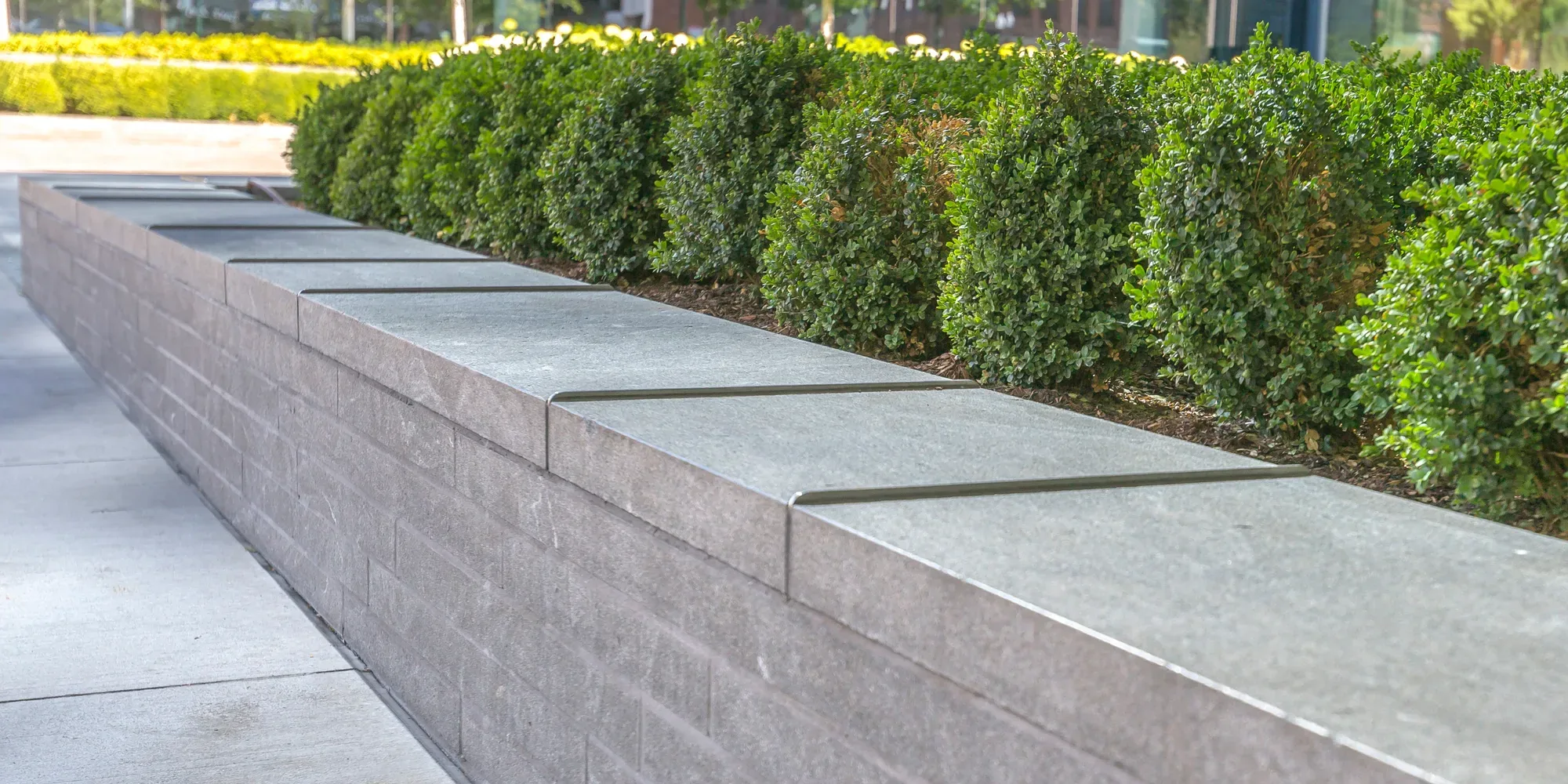 Close-up of a low rendered retaining wall with sandstone-look capping stones