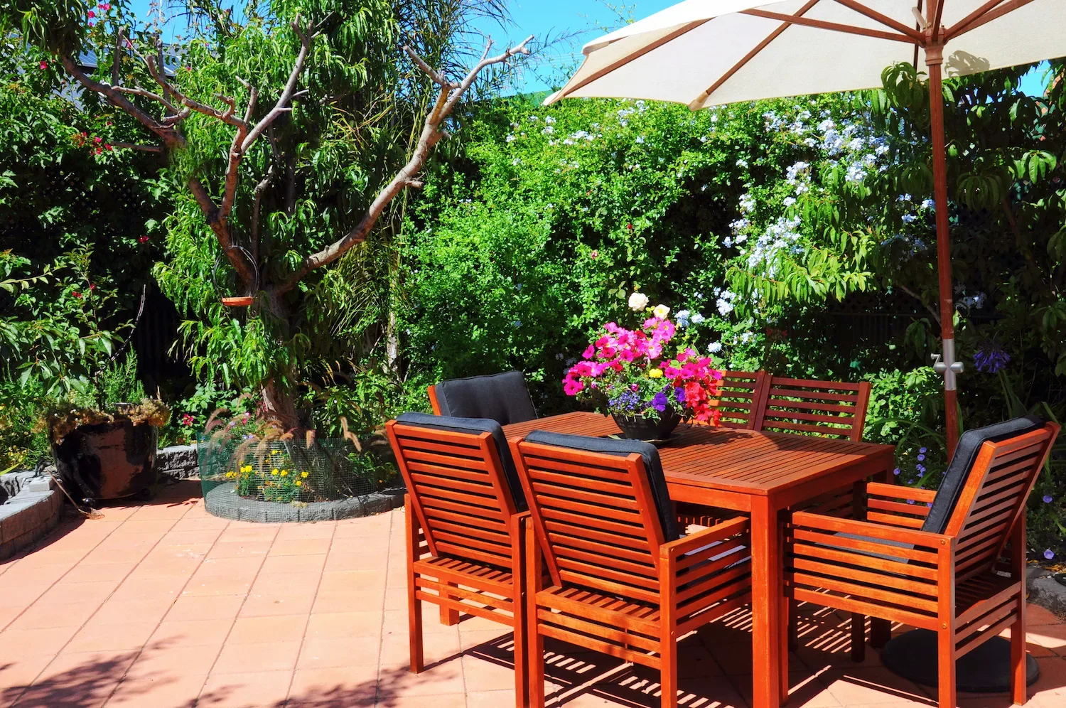 Sunny paved courtyard patio with a timber outdoor dining table