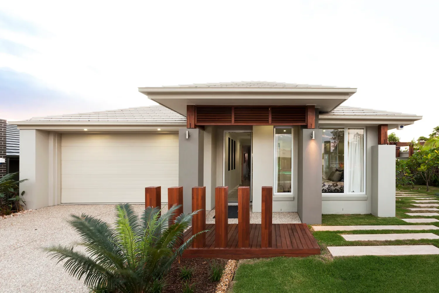 Modern house facade with a small elevated timber entry deck and gravel driveway